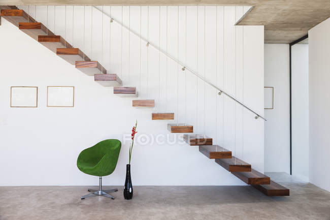 Chair under floating staircase in modern house — Stock Photo