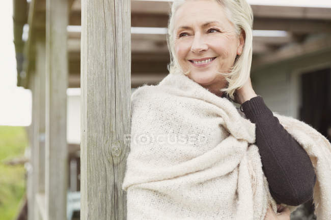 Sorridente donna anziana indossa scialle sul portico — Foto stock