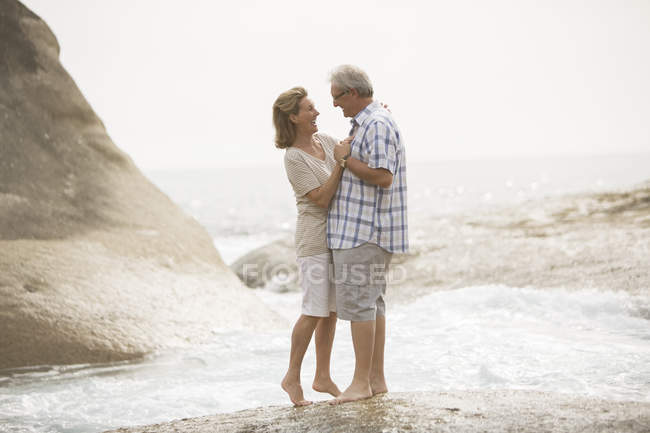 Couple aîné étreignant sur la plage — Photo de stock
