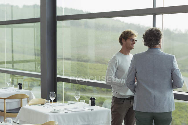 Hombres hablando en la ventana del comedor bodega - foto de stock