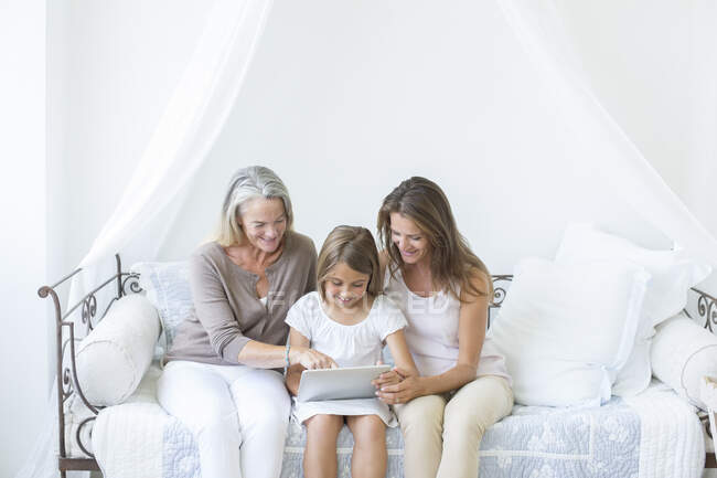 Multi-generación de mujeres que utilizan tableta digital en el sofá cama - foto de stock