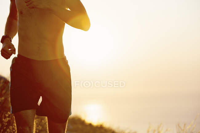 Голый мужчина с грудью бежит на закате — стоковое фото