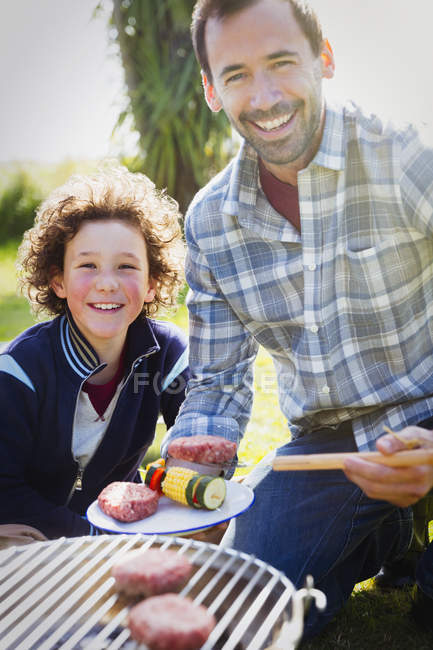 Portrait smiling father and son barbecuing — Stock Photo