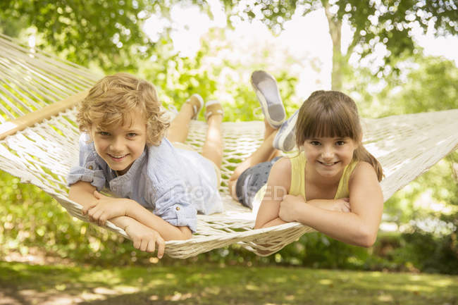 Niños felices que relajan juntos en hamaca - foto de stock