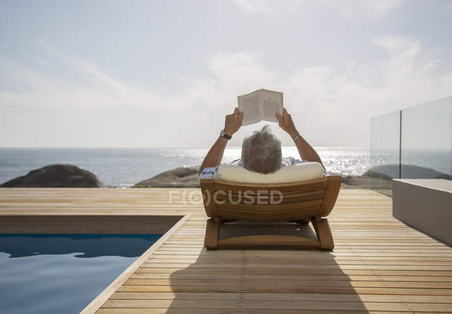 Older man reading by pool — Stock Photo