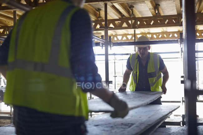 Bauarbeiter heben Sperrholz auf Baustelle — Stockfoto