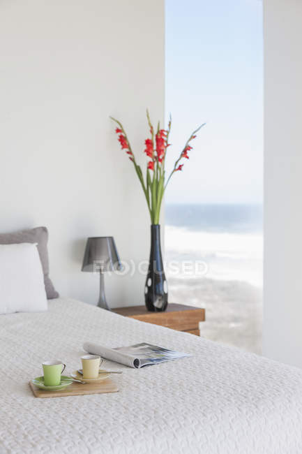 Bandeja de desayuno en la cama en dormitorio moderno con vista al mar - foto de stock