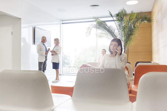 Woman talking on cell phone in hospital lobby — Stock Photo