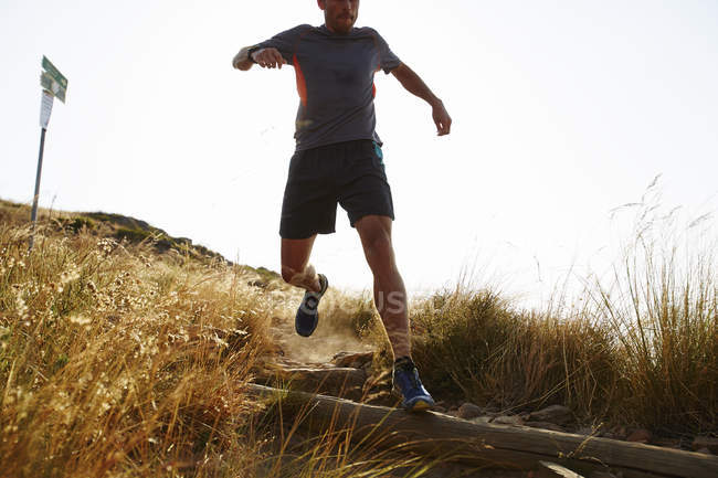 Male runner descending trail hillside — Stock Photo