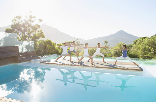 Young attractive people practicing yoga at poolside — Stock Photo