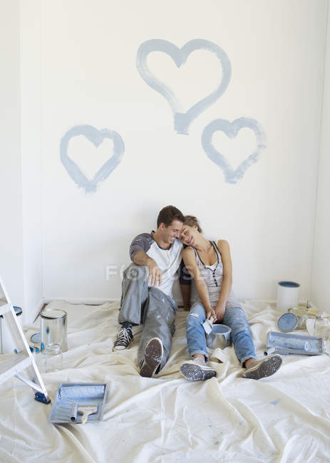 Pareja pintando corazones azules en la pared - foto de stock