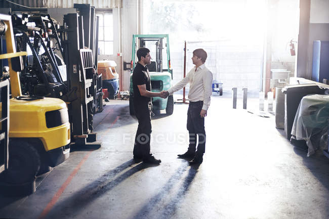 Mécanicien et poignée de main du client dans l'atelier de réparation automobile — Photo de stock