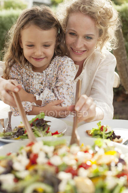 Madre e hija comiendo en el jardín - foto de stock