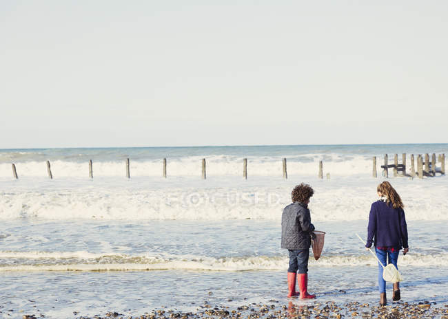 Brother and sister with nets in ocean surf — Stock Photo