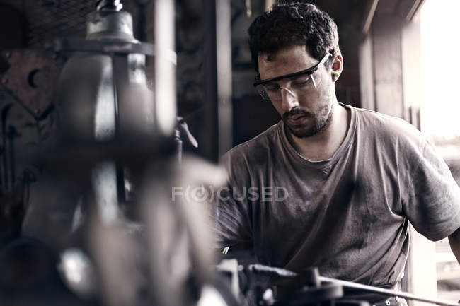 Focused blacksmith shaping iron in forge — Stock Photo