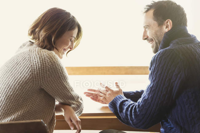 Пара сміється в светрах за столом — стокове фото