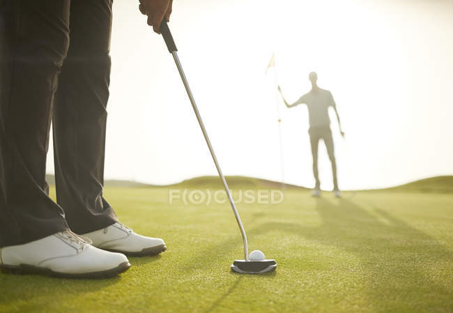 Imagen recortada del hombre poniendo en campo de golf - foto de stock