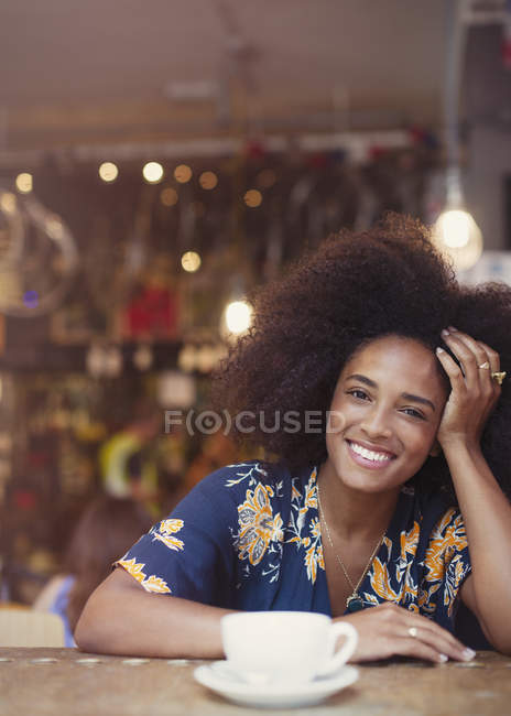 Retrato sonriente mujer con afro beber café en la cafetería - foto de stock