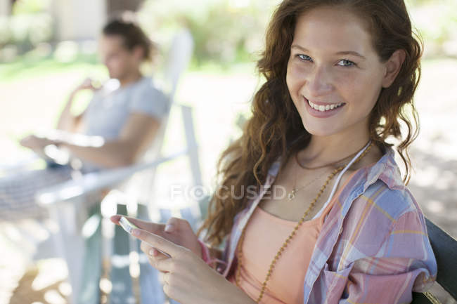 Mujer usando el teléfono celular en el banco - foto de stock