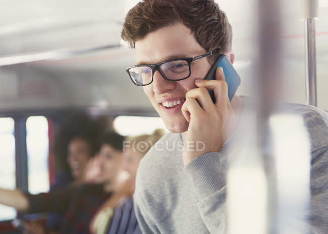 Homme souriant avec des lunettes parlant sur un téléphone portable dans le bus — Photo de stock