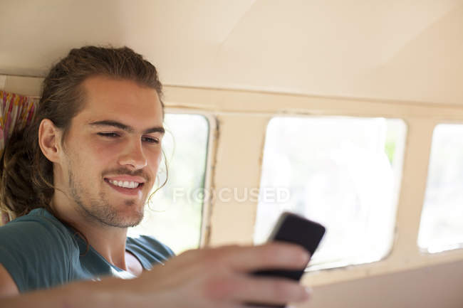 Man using cell phone in camper van — Stock Photo