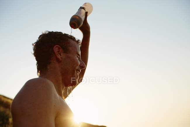 Tired runner pouring water on head — Stock Photo
