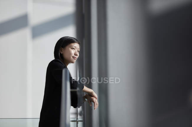 Femme d'affaires pensive regardant par la fenêtre ensoleillée du bureau — Photo de stock