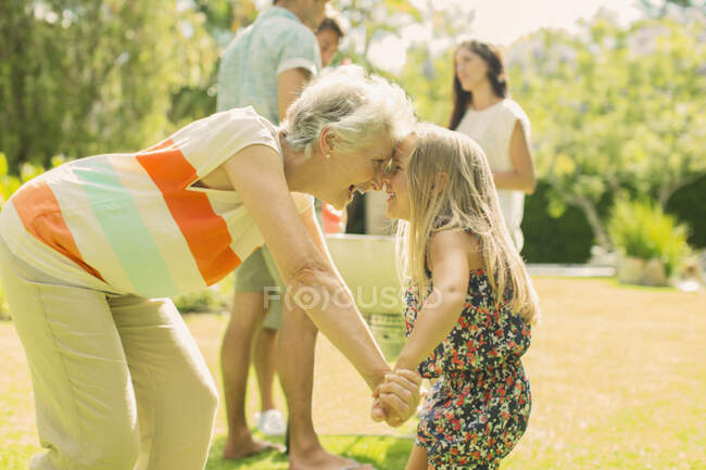 Grandmother and granddaughter rubbing noses in backyard — Stock Photo