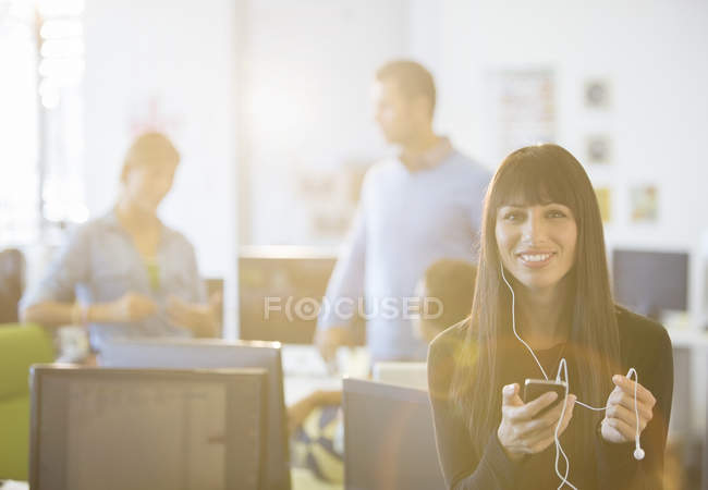 Businesswoman listening to mp3 player in office — Stock Photo
