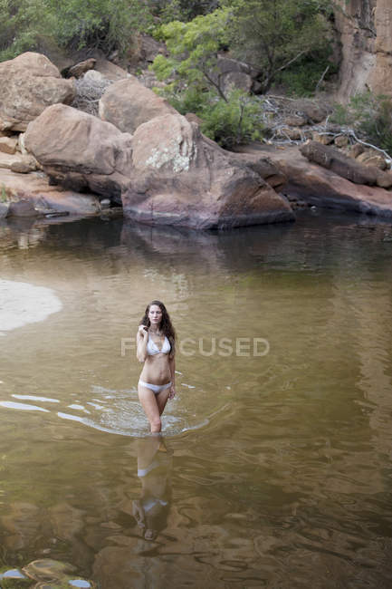 Femme pataugeant dans la piscine au milieu du rocher — Photo de stock
