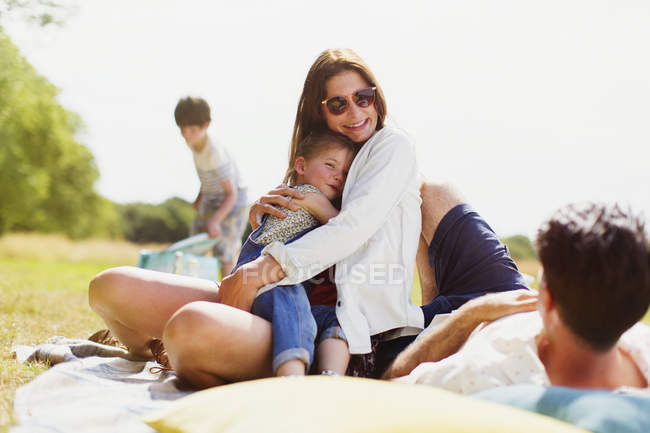 Família relaxante em cobertor em campo ensolarado — Fotografia de Stock