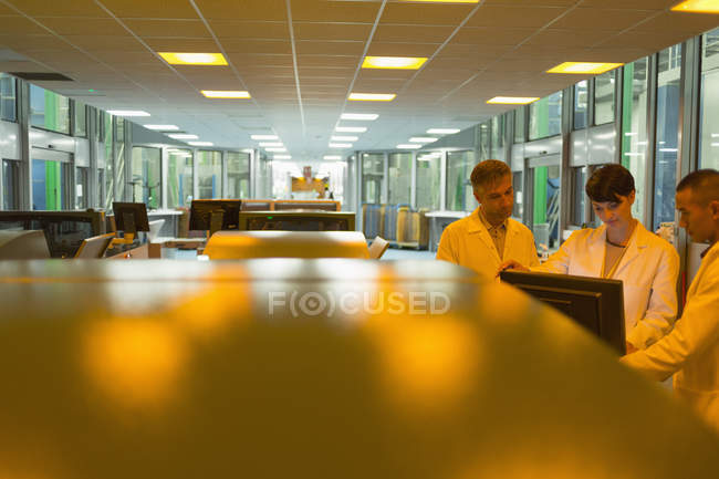 Workers at computer near printers in factory — Stock Photo
