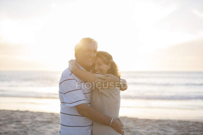 Casal sênior abraçando na praia — Fotografia de Stock