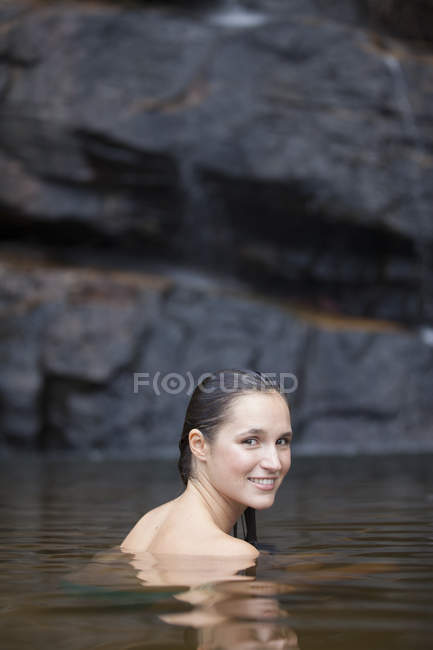 Женщина плавает в бассейне против скалы — стоковое фото
