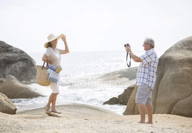 Homme plus âgé prenant des photos de petite amie sur la plage — Photo de stock