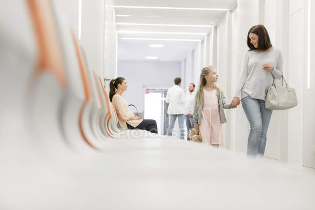 Mother and daughter holding hands walking in hospital corridor — Stock Photo