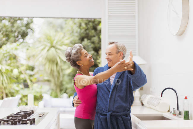Playful mature couple dancing in kitchen — Stock Photo