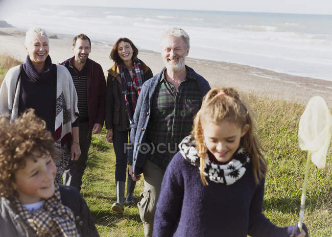 Familia multigeneracional caminando por sendero de playa cubierto de hierba - foto de stock