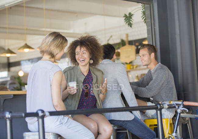 Laughing friends hanging out drinking coffee on cafe patio — Stock Photo