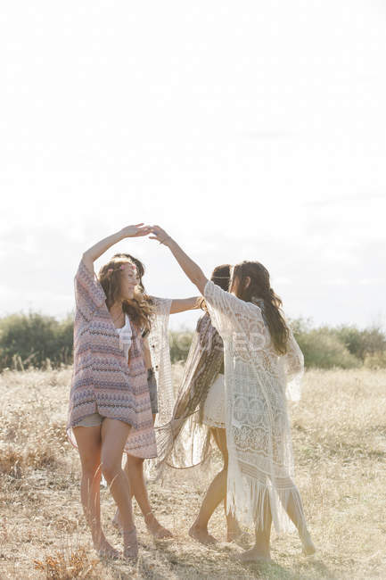 Boho mulheres dançando em círculo no campo rural ensolarado — Fotografia de Stock