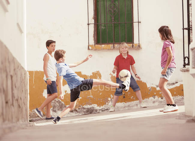 Niños jugando con pelota de fútbol en el callejón - foto de stock