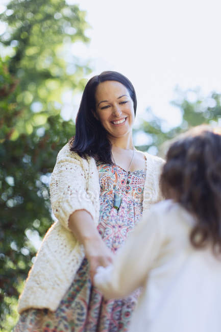 Smiling mother and daughter holding hands outdoors — Stock Photo