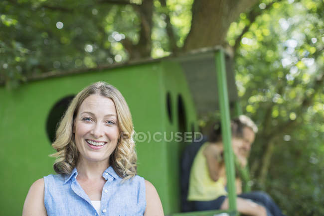 Woman smiling with treehouse in background — Stock Photo