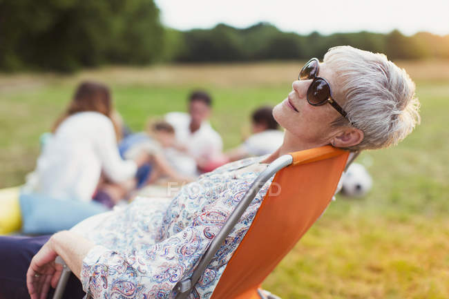 Seniorin entspannt sich auf Stuhl im Feld — Stockfoto