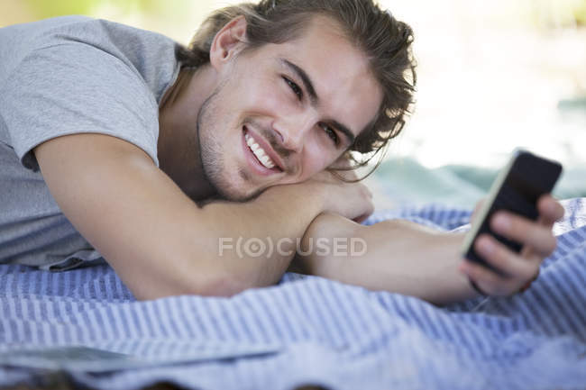 Чоловік використовує мобільний телефон на пікніку ковдру — стокове фото
