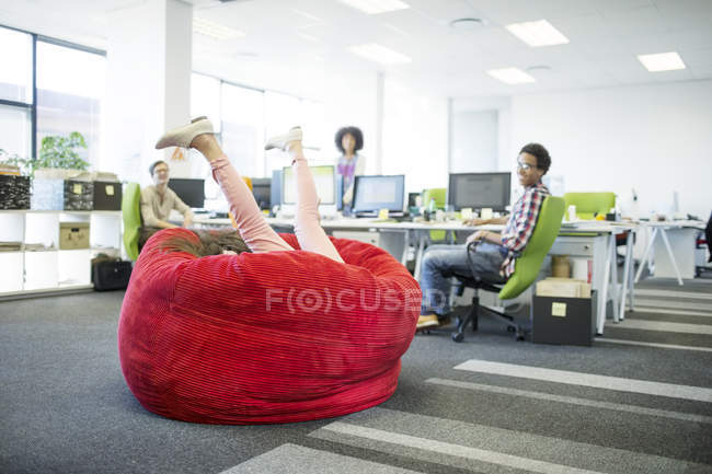 Ділова жінка грає в кріслі для мішків в офісі — стокове фото