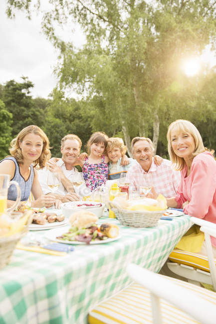 Сім'я багато поколінь обідає за столом на задньому дворі — стокове фото