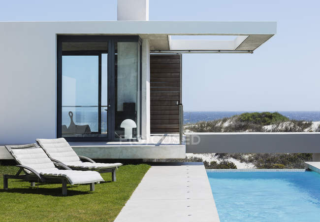 Гостиные стулья и бассейн у современного дома с видом на океан — стоковое фото
