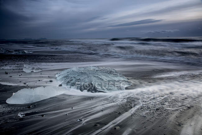 Лед на штормовом пляже холодного океана, Йокулсарлон, Исландия — стоковое фото