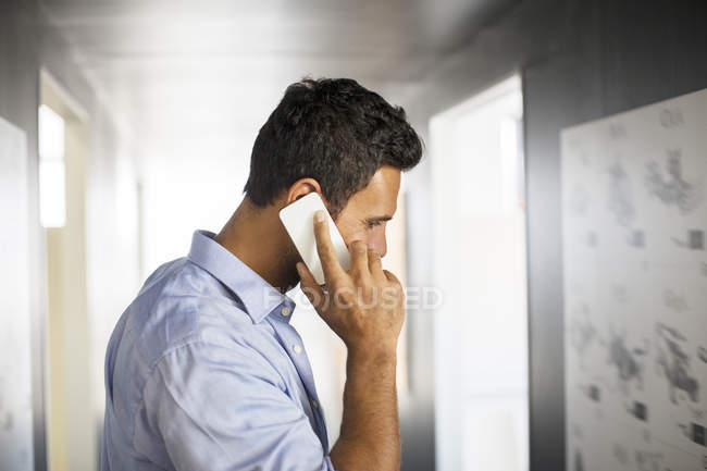 Uomo d'affari che parla al cellulare nel corridoio — Foto stock